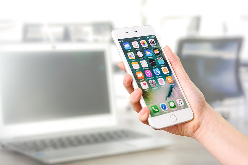 Hand holding white smartphone with blurred office background