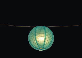 Glowing teal paper lantern hanging against dark night background