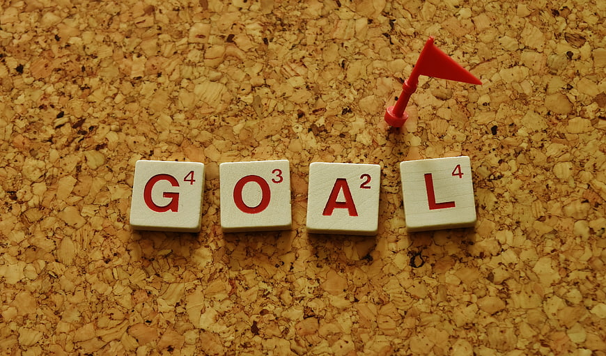 Scrabble Tiles Spelling Goal on Cork Board with Red Flag
