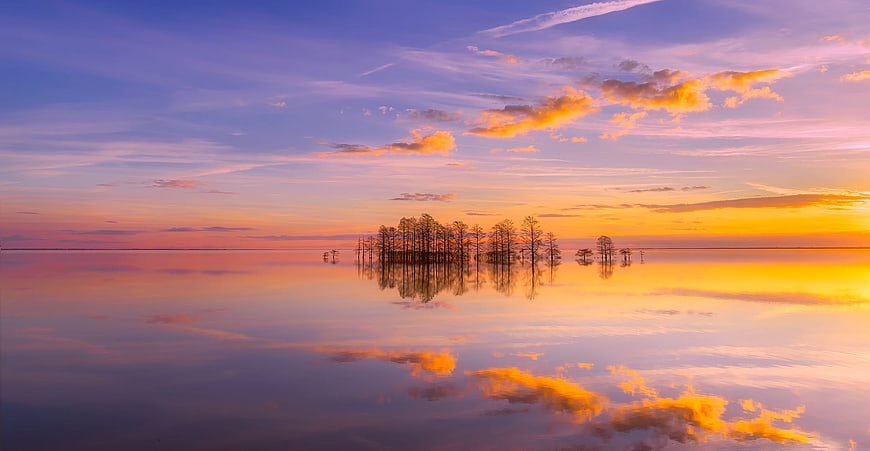 Serene Sunset Reflection Over Lake With Silhouetted Trees