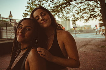 Two Smiling Women Friends Embracing in Urban Park