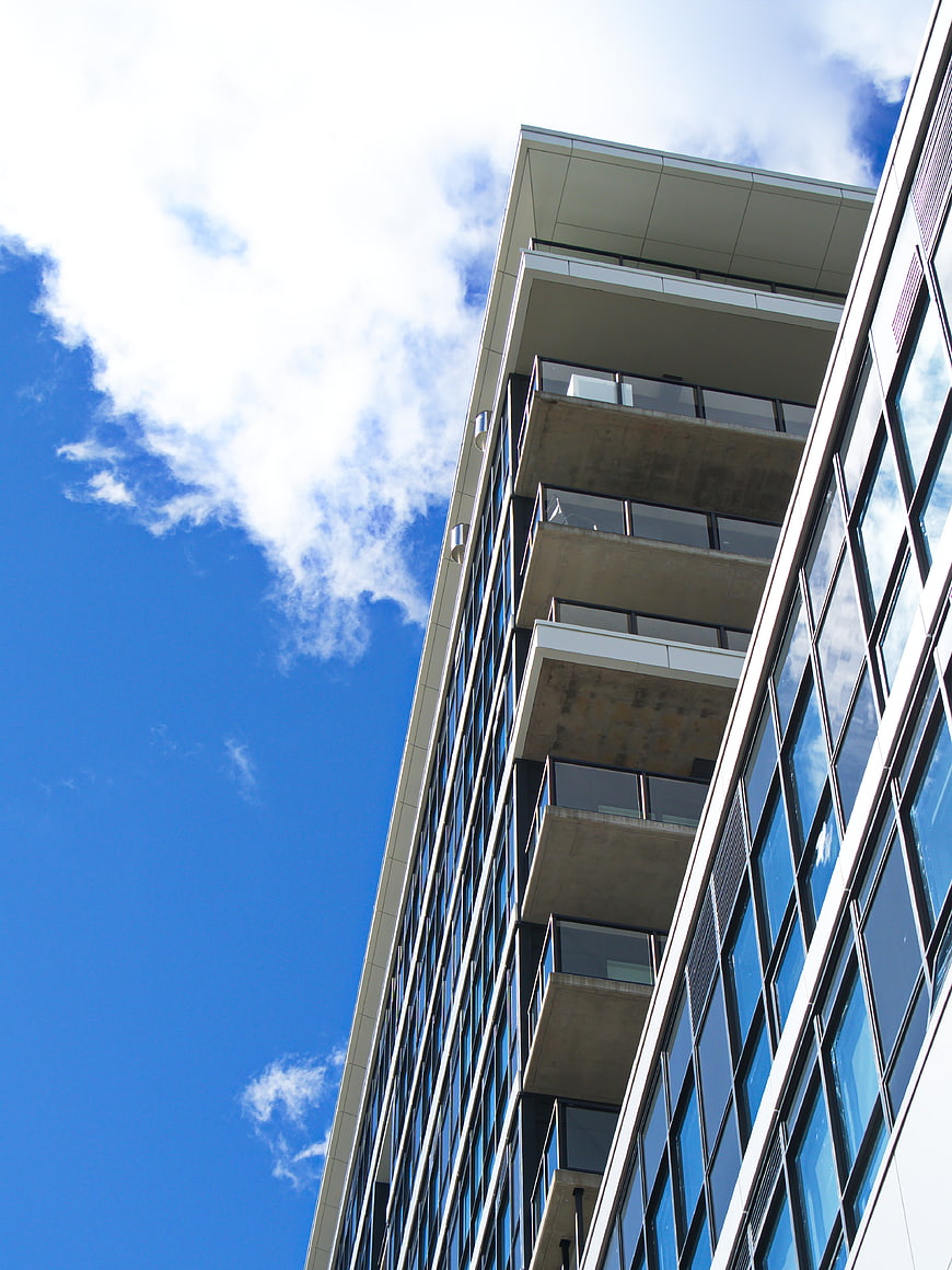 Low angle view of modern glass office building against blue sky