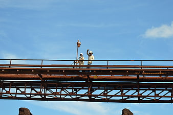 Construction workers on steel bridge against blue sky