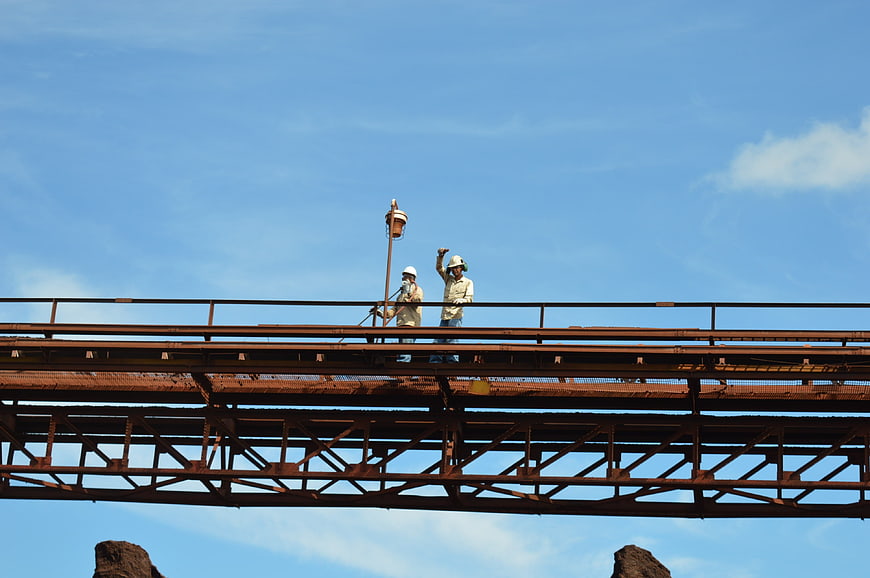 Construction workers on steel bridge against blue sky