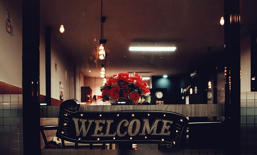 Vintage Welcome Sign with Red Roses in Coffee Shop Window