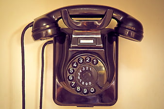 Vintage black rotary telephone on cream wall