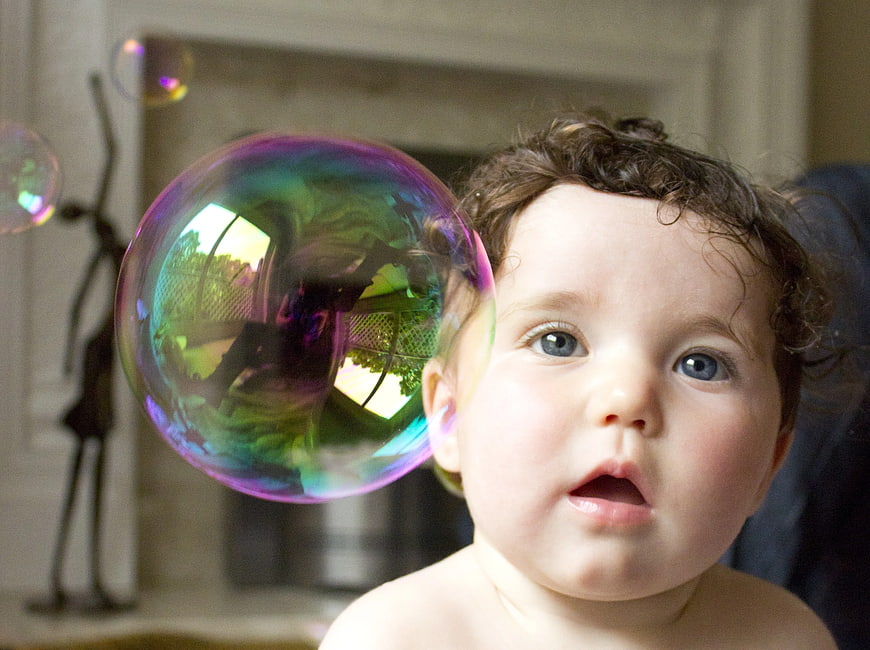 Curious Baby Watching Large Colorful Soap Bubble Indoors