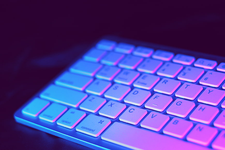 Close-up of Apple Keyboard with Neon Blue and Purple Lighting