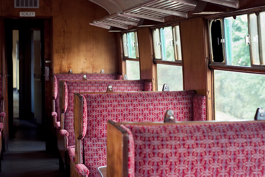 Vintage Train Interior with Red Patterned Seats and Wooden Walls