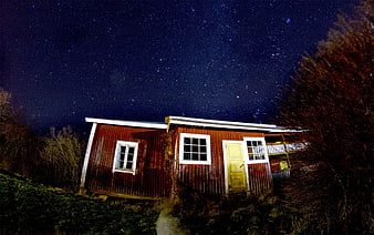 Red wooden cabin under starry night sky