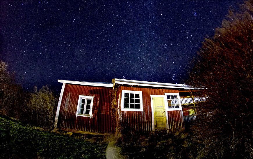 Red wooden cabin under starry night sky