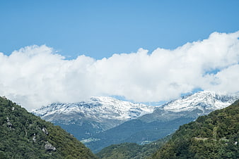 Snow-Capped Mountains Rising Above Green Forested Hills