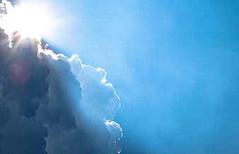 Sun rays breaking through clouds in blue sky