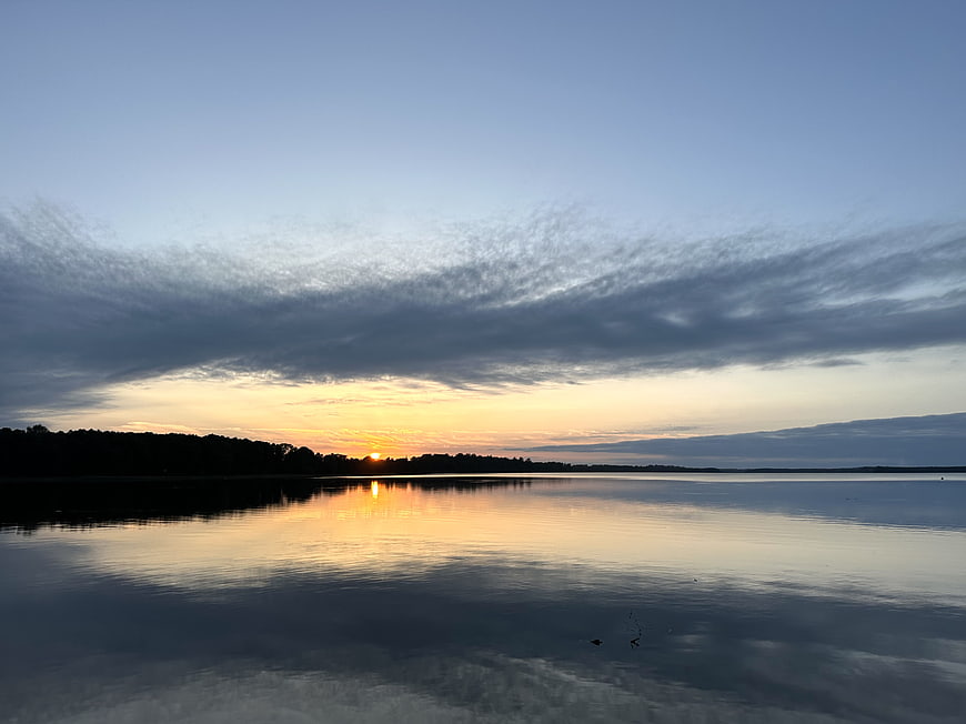 Serene Lake Sunset with Cloud Reflections and Silhouette
