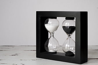 Dual Hourglass Timepiece in Black Frame on White Surface