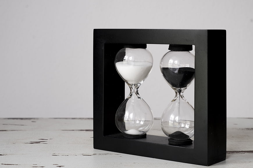 Dual Hourglass Timepiece in Black Frame on White Surface