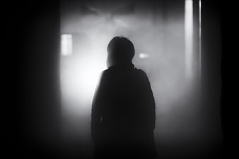 Silhouette of a person standing in dark foggy atmosphere