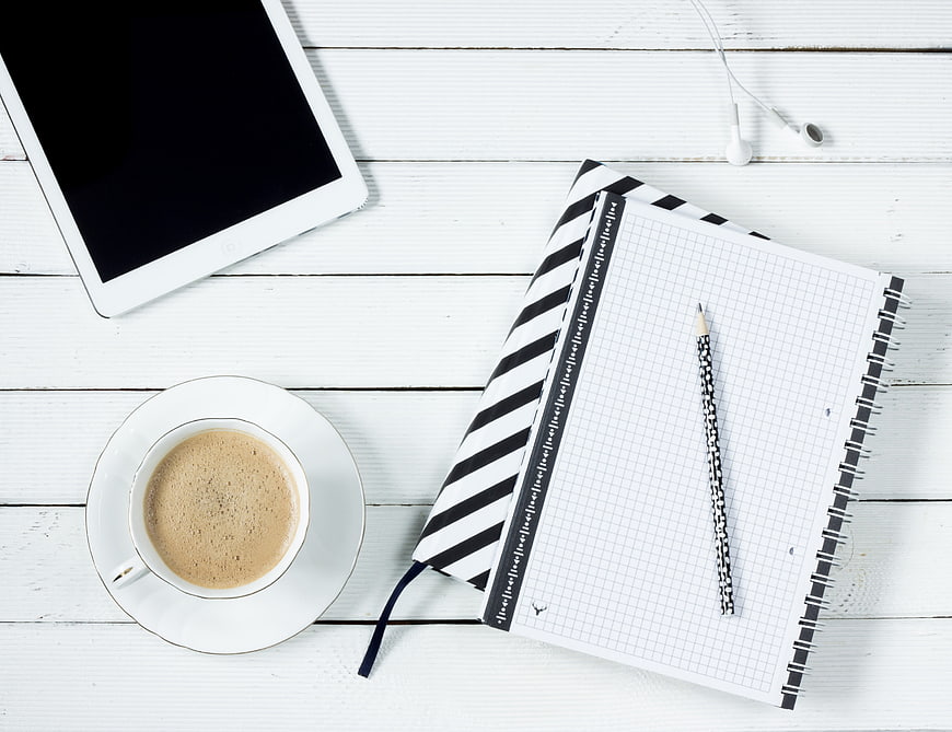 Flat lay workspace with coffee, tablet, and notebook