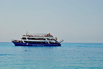 Blue and white cruise ship sailing on calm turquoise sea