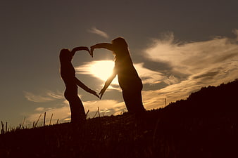 Silhouette of Two Women Forming Heart Shape at Sunset
