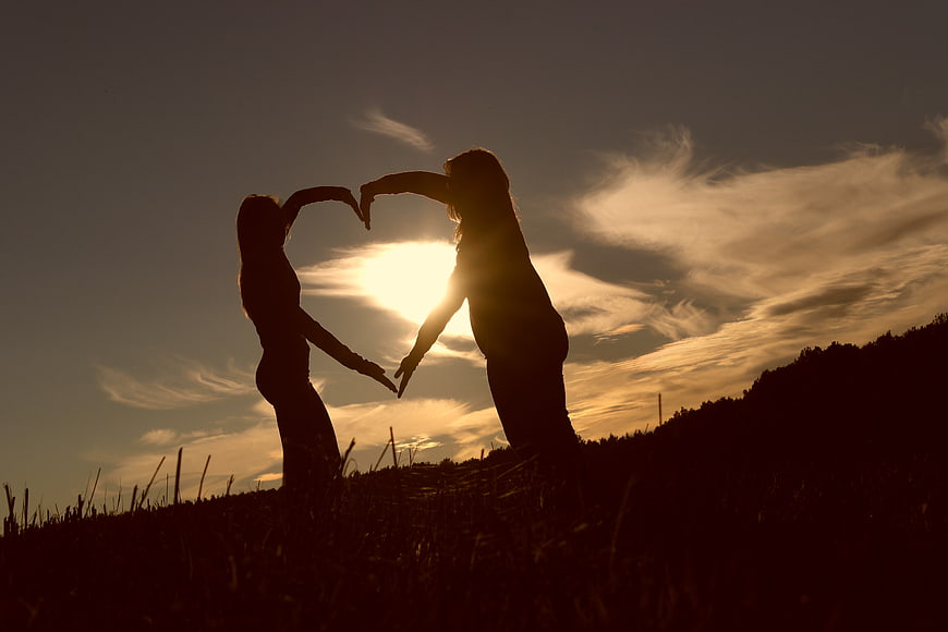 Silhouette of Two Women Forming Heart Shape at Sunset