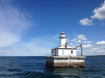 White Lighthouse on Concrete Base in Blue Ocean