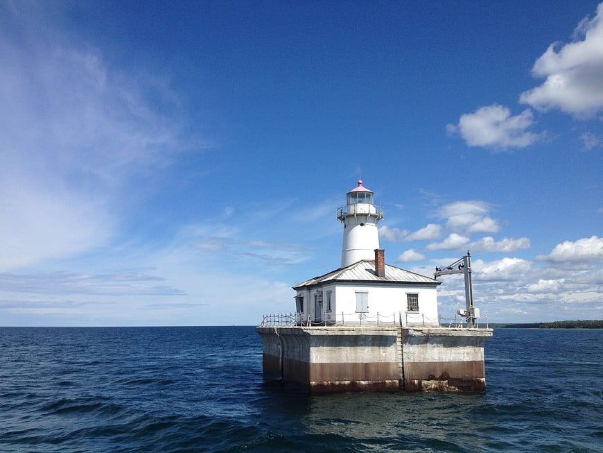 White Lighthouse on Concrete Base in Blue Ocean