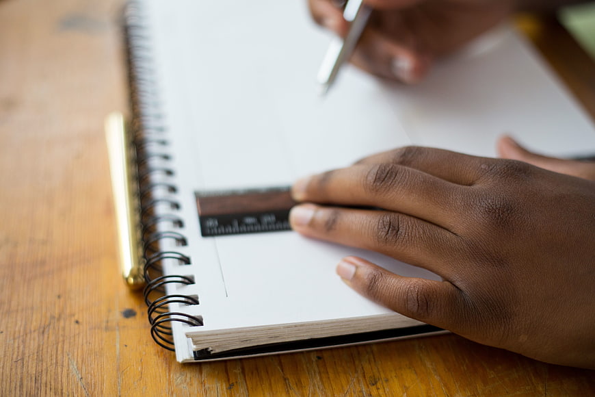 Close-up of hands drawing with ruler on notebook