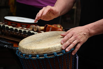 Close-up of hands playing djembe drum with blue ropes