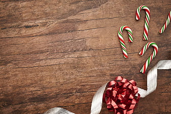 Christmas Candy Canes and Red Bow on Wooden Background