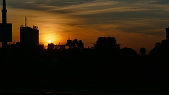 Silhouette of city skyline against dramatic orange sunset sky