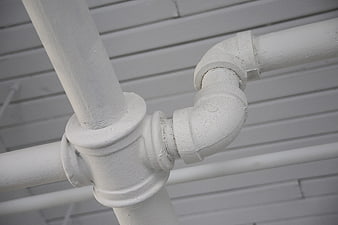 Close-up of white industrial pipes and fittings against siding