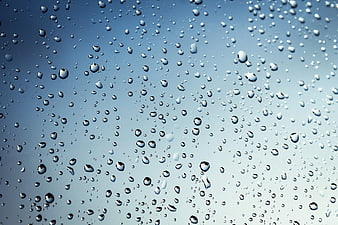Water droplets on glass against blue sky background