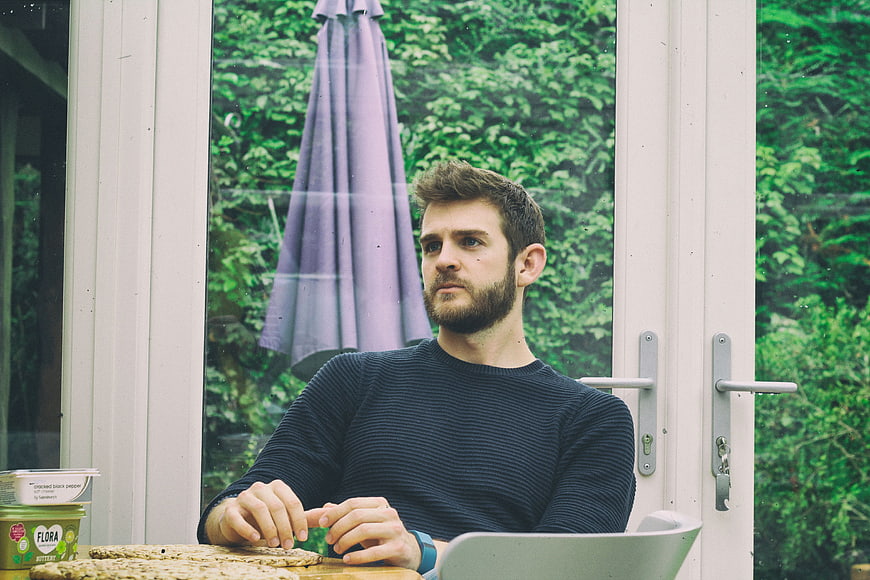 Man working on laptop in conservatory with garden view