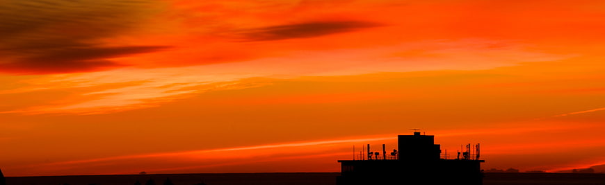 Vibrant Orange Sunset Sky with Silhouetted Building Roof