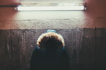 Anonymous figure in fur hood under fluorescent light