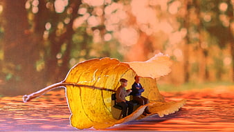 Miniature Men Sitting on Bench Under Autumn Leaf Canopy