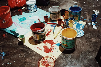 Messy paint buckets and supplies on concrete floor