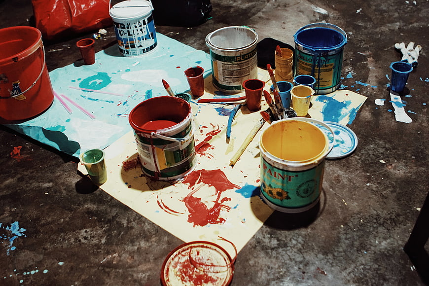 Messy paint buckets and supplies on concrete floor