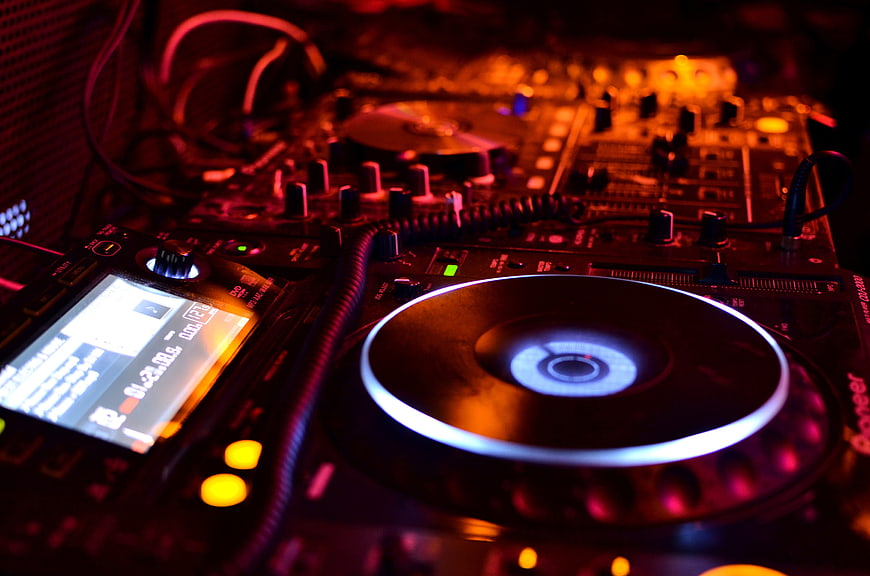 Close-up of DJ turntable and mixer in club lighting