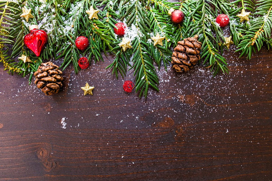 Christmas pine branches with ornaments and snow on wood