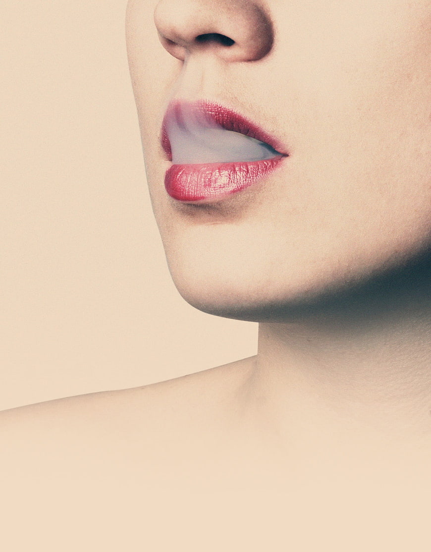 Close-up of woman's lips with red lipstick and smoke
