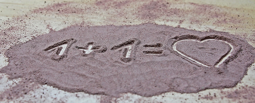 1 + 1 equals heart drawn in purple sand
