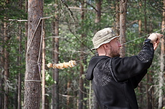 Man drying sliced mushrooms on string in pine forest