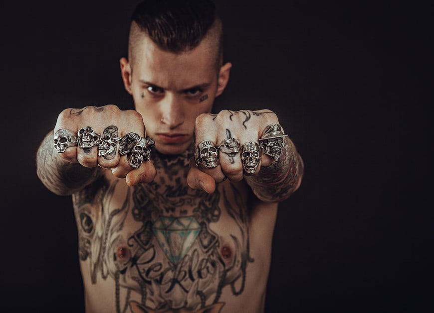 Tattooed Man With Skull Rings And Fists