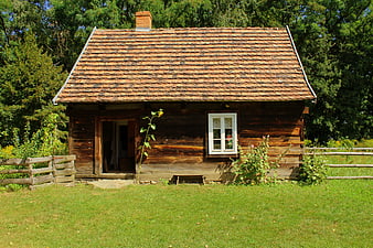 Rustic wooden cottage with tiled roof in rural landscape