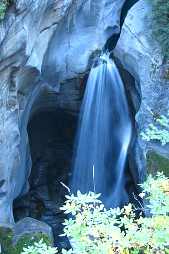 Silky waterfall cascading through rocky cave opening