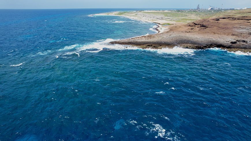 Aerial View of Rocky Coastline with Deep Blue Ocean Waves