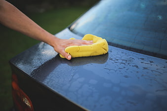 Hand washing black car with yellow sponge