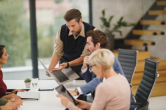 Business team meeting discussing laptop in modern office